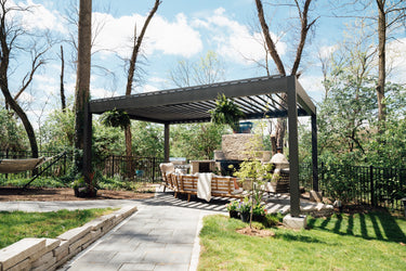 Outdoor patio area with pergola, outdoor furniture, and barbecue grill in a garden setting.