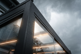 Modern conservatory structure with glass panels and a dark sky.