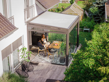 Outdoor patio area with a conservatory and people sitting at a table.