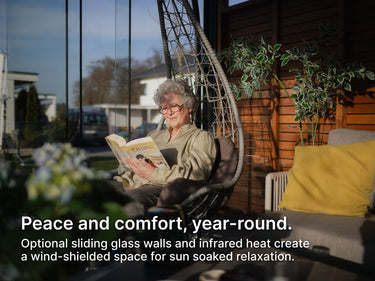 Woman reading a book in a modern pergola setting with plants and furniture.