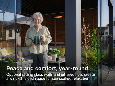 Woman standing on a patio in a pergola with sliding glass walls and plants