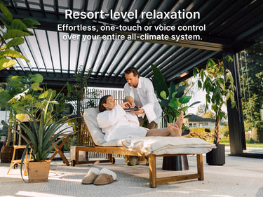 Person relaxing on a lounge chair with a baby, surrounded by plants and modern decor.