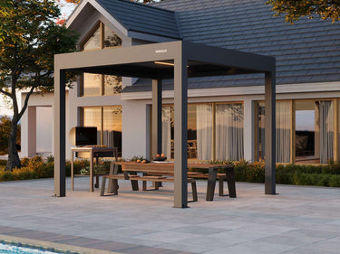 Patio with pergola, table, and chairs in front of a house.