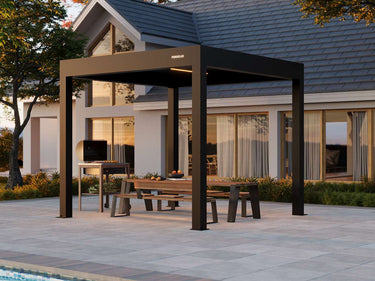 Black pergola with outdoor furniture on a patio area in front of a house.