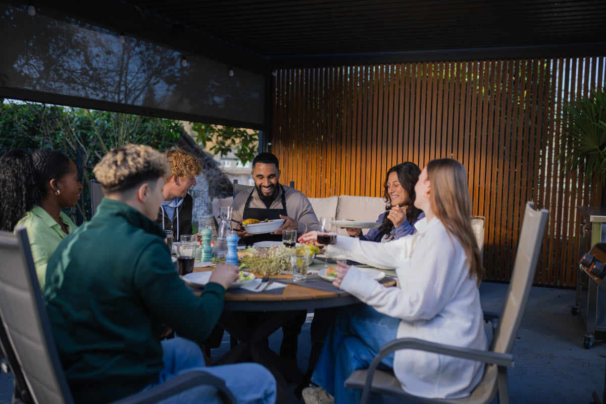 Friends dining beneath a modern PERGOLUX aluminium pergola